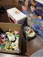 Photo showing box of assorted small plastic toy figures, View-Master box, 'Pirates Loot' black box, and vintage wood toy kit box