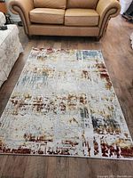 Full view of the area rug placed on wood flooring near a leather sofa, showing overall size and pattern.