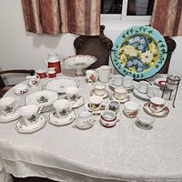 Various dishes and teacups arranged on table showing overall lot contents including holiday and floral themed pieces.