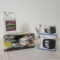 Photo showing fog machine box, fog solution container, and two boxes of strobe light.