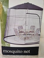 Photo of boxed large patio umbrella mosquito netting showing net surrounding outdoor table and chairs.