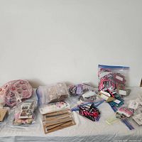 Wide shot of various loot bag items arranged on a white surface including jewelry packets, stationery, and eraser packs