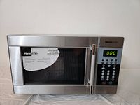 Full front view of Homestyles stainless steel microwave oven with visible handle and control panel.