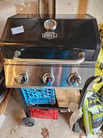 Front view of the black Expert Grill BBQ showing lid with temperature gauge and three stainless steel knobs.