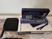 Console, original box, dock, zip case and stylus displayed
