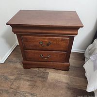 Front view of one nightstand showing two drawers with metal handles and wood finish.