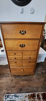 Front view of solid wood tall boy dresser showing drawer handles and overall condition