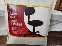 Photo of the unopened box showing the chair image and product description in English and French including adjustable height 75 cm to 82 cm and chair dimensions 53 cm wide by 47 cm deep.