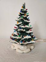 Front view of the ceramic Christmas tree light showing multi-colored bulbs and snow-tipped branches.