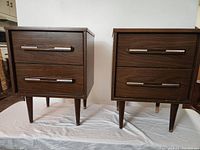 Front view of both nightstands showing overall design, drawer arrangement, handles, and leg style