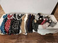 Full lot view showing fleece scarves with snowflake patterns, knit scarves, gloves, and hat arranged on table