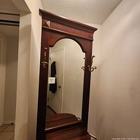 Full view of the solid wood hall tree showing the mirror, decorative top molding, and the base with umbrella stand.