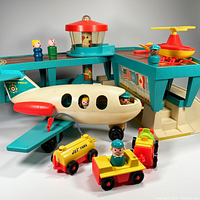 Photo showing the assembled airport base with helicopter, airplane with passengers seated inside, tram, jet fuel tanks, suitcases, and five wooden-bodied figures placed on the set.