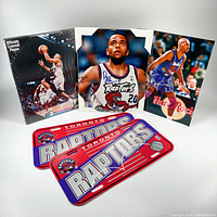 Collection of 1990's Toronto Raptors basketball items including two autographed photos, a sealed plak-it plaque and unused novelty license plates.