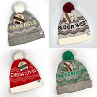 Four City of Neighbourhoods Toronto knit toques displayed in a 2x2 grid showing all designs and colors with tags attached.