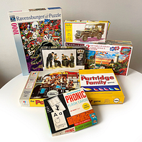 Photo showing the full lot including Ravensburger 1000-piece puzzle, Heller Jeep Willys model kit, Partridge Family game boxes, phonic flash cards, sealed Keepsakes puzzle bundle, and Master Box WWII Tankman model kit.