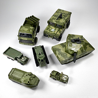 Overview of seven assorted military vehicle toys including missile launcher truck, jeeps, tanks with mounted weapons, all painted green or camouflage with military markings.
