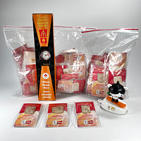 Photo showing 1998 Nagano Winter Olympics official McDonald's watch in original sealed box, multiple plastic bags of Coca Cola pins, and the McDonald's Miga mascot toy on a snowboard.