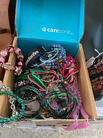 Top view of box with assorted bead bracelets and metal bangles in various colors and styles