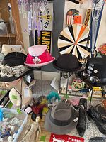 Multiple decorative hats arranged on hat stands and a pair of leather shoes on the floor, various patterns and materials visible.