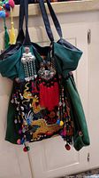 Front view of green Asian themed purse with colorful tassels, beads, and embroidered dragon and phoenix design