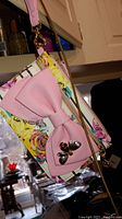 Front view of small floral and stripe patterned purse with large pink bow and heart detail on front