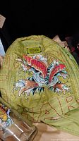 Close-up view of the green Ed Hardy backpack showing embroidered koi fish design and Ed Hardy label.