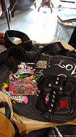 Ed Hardy bag laid out showing front colorful graphics, pockets, strap, and tags