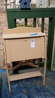 Front view of small beige painted wooden desk with fold-down front showing paint wear and scratches.
