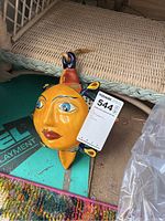 Front-facing photo showing the vibrant colors and facial details of the ceramic sun wall hanging with a metal ring for hanging.