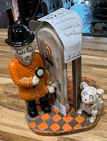 Front view of the ceramic candle holder showing figure in orange coat and dog with checkered base.