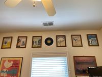 Six framed music artworks displayed on wall above window with an MGM record centered among them.