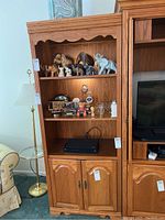 Front view of wooden bookcase showing three shelves partly filled with decorative items and lower double-door cabinet.