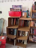 Books on shelves and stacked in cardboard boxes, showing variety of sizes and cover types