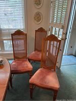 Set of three wooden dining chairs with rattan backs and velvet seat cushions in a dining room setting.