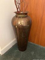 Full view of the tall metal vase showing texture and braided rope detail.