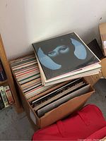 Cardboard box filled with vinyl records topped by a Barbra Streisand album with a blue-tinted portrait on black background