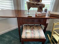Singer sewing machine mounted in wooden table with fold-out sides, top view showing machine and box labeled 'buttonholer'
