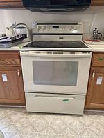 Full view of white Jenn-Air range installed between cabinets under hood