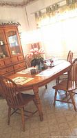 Oval wooden kitchen table with four chairs placed around it in a kitchen setting.