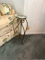 Side view of glass and metal side table next to patterned sofa on carpeted floor