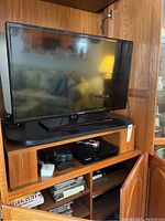 Samsung 32-inch television on wooden shelving with couch reflected on screen