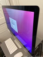 Angled front view showing 27-inch iMac display booted to setup screen, keyboard and mouse in front