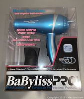Front view of BaByliss Pro hair dryer in packaging showing product features such as 2000 watts, nano titanium technology, ion generator, lightweight design.