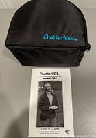Black zippered carrying case with embroidered 'ChatterVox' logo placed behind the ChatterVox Model 6 user guide.