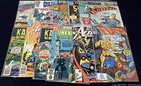 12 vintage DC Comics including Superman, Flash, Justice League, Justice Society, Kamandi, Unknown Soldier, Action Comics, all in plastic sleeves.