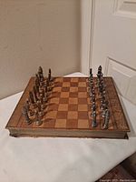 Overall view of the vintage leather book chess set opened with all pieces arranged on the board showing the worn leather and checkered playing surface.