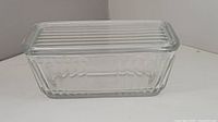 Front angled view of ribbed glass refrigerator dish with lid showing rectangular ribbed pattern on lid and sides