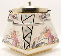 Full view of antique biscuit barrel showing floral and geometric triangle panel design with metal lid and handle.