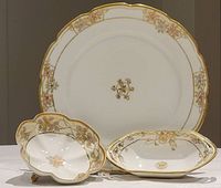 Front view of the three Nippon porcelain pieces: large plate, footed bowl, and small dish, showing hand painted floral and gilt details.